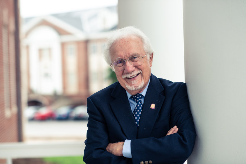 Dr. Angelo Volpe stands with his arms crossed leaning against a column