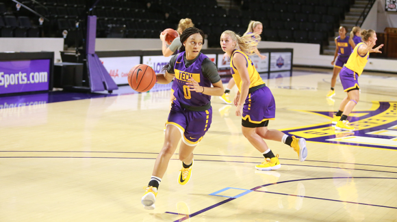 Tech women's basketball still of woman dribbling ball in a scrimmage.