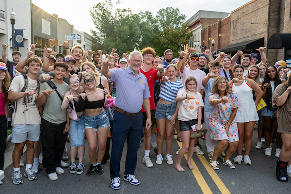 Phil Old, President, and a group of students gesturing a Wings Up to the camera. 
