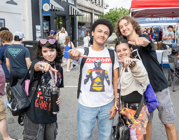 Four students posing for the camera while giving a Wings Up.